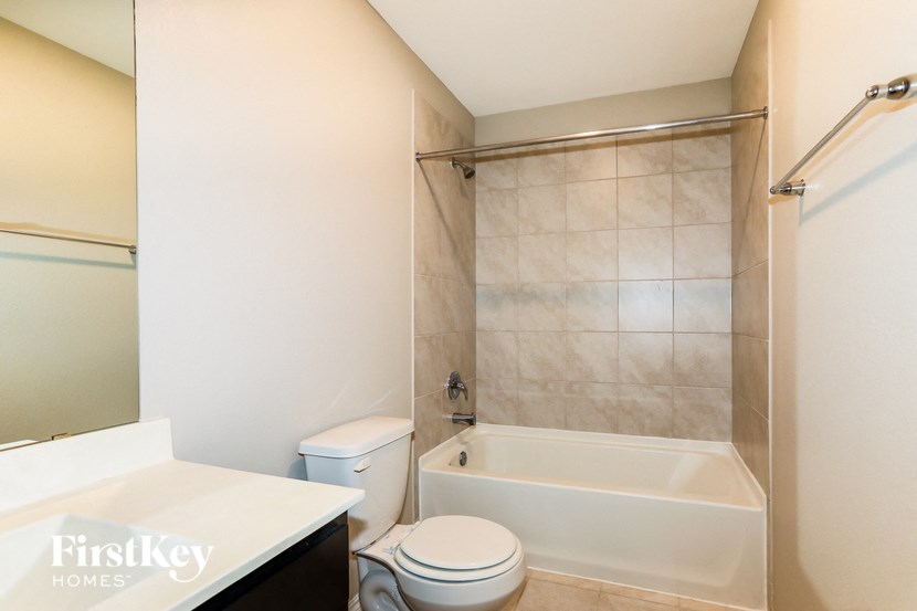 A white toilet sits next to a bathtub in a bathroom.