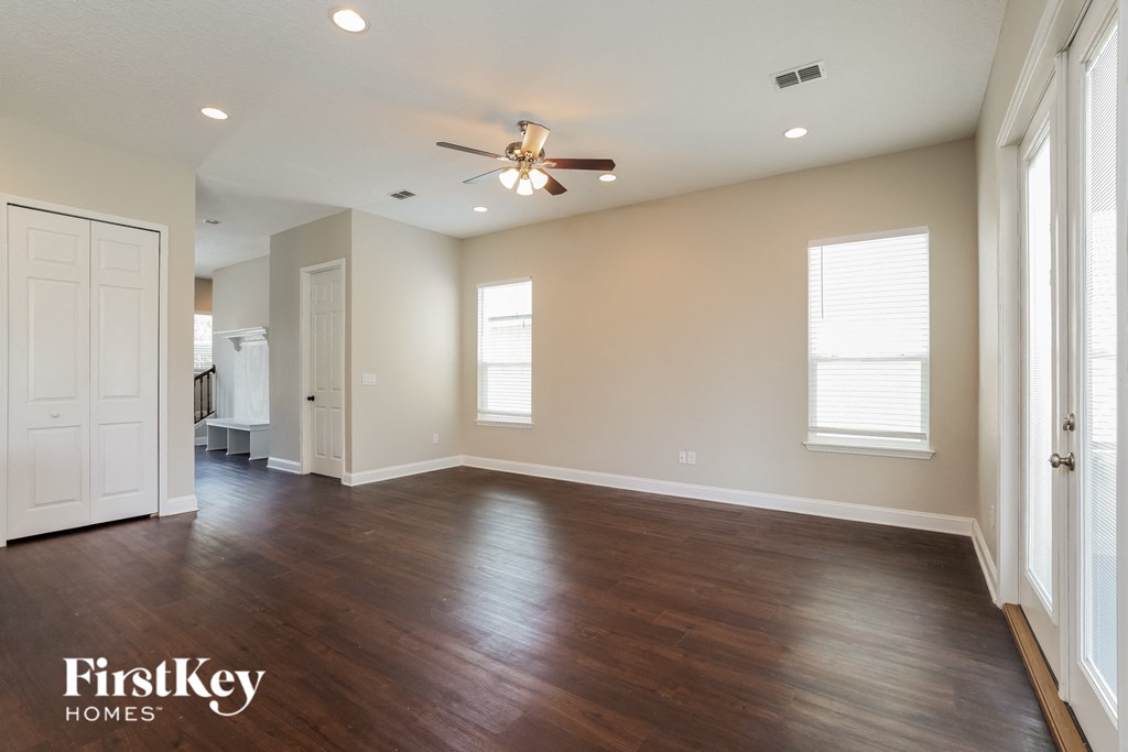 an empty living room with wood floors and a ceiling fan