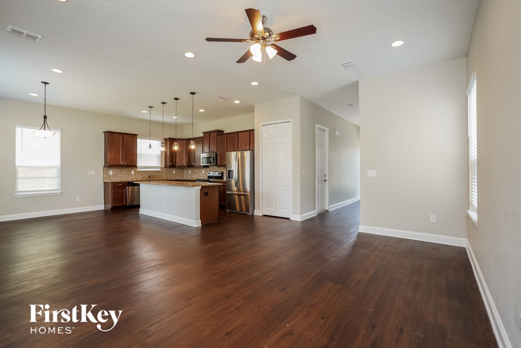 an open kitchen and living room with wood flooring and a ceiling fan
