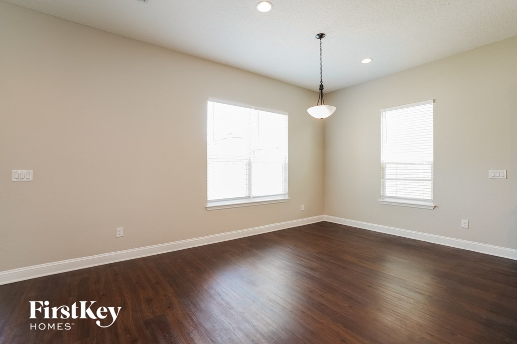 an empty living room with wood floors and two windows