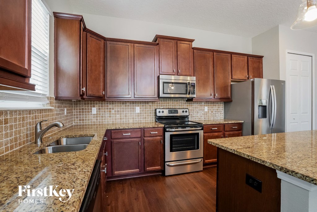 a kitchen with wooden cabinets and granite counter tops and stainless steel appliances