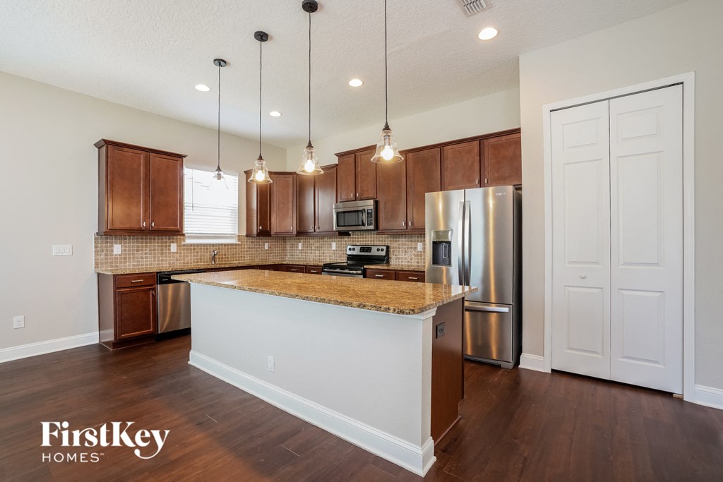 a kitchen with an island and a stainless steel refrigerator