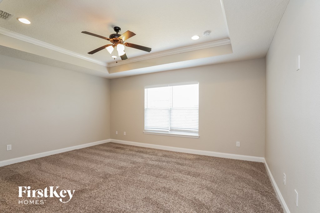 an empty living room with a ceiling fan and a window
