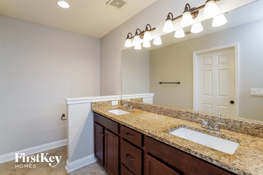 the master bathroom has dual sinks and a large mirror