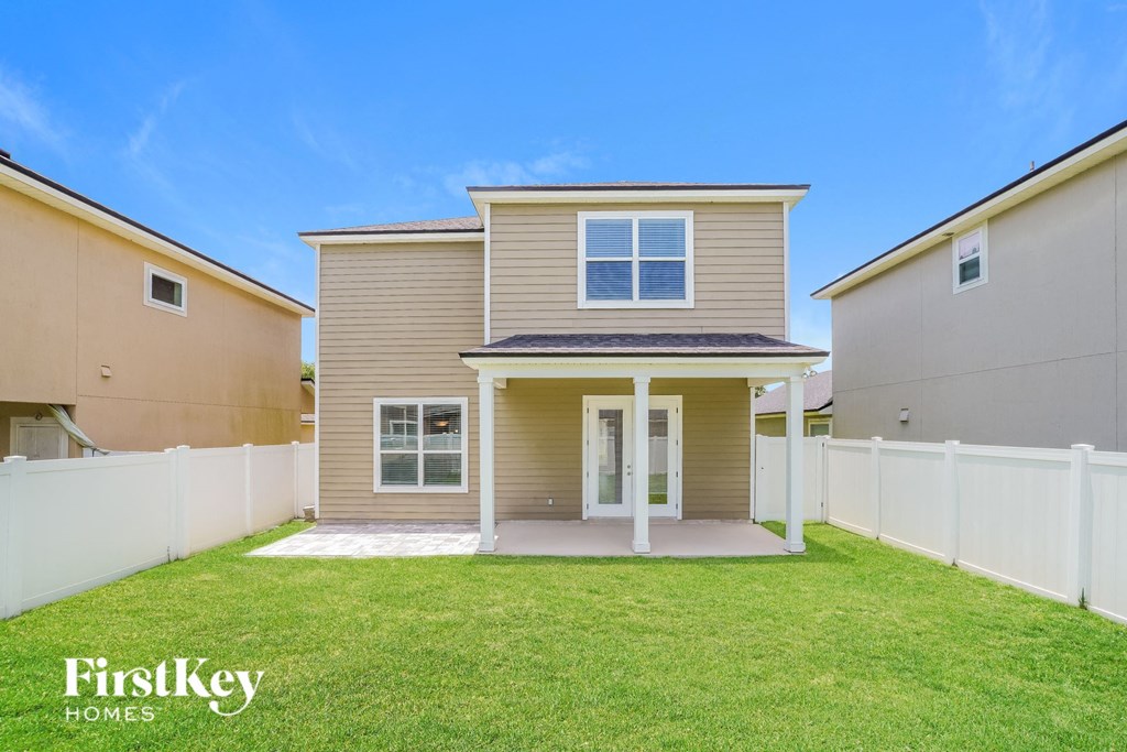 a tan house with a grassy yard and a white fence