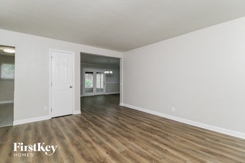 an empty living room with white walls and wood floors