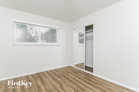 a bedroom with a closet and a window and wood flooring