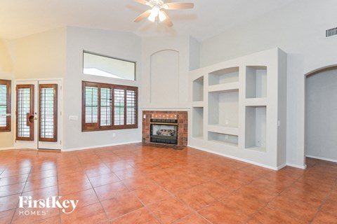 A living room with a fireplace and a fan.