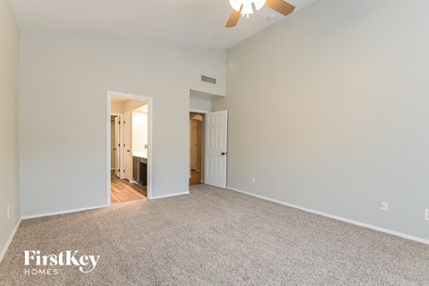 A spacious room with a carpeted floor and a ceiling fan.