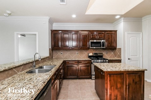 A kitchen with brown cabinets and a granite countertop.