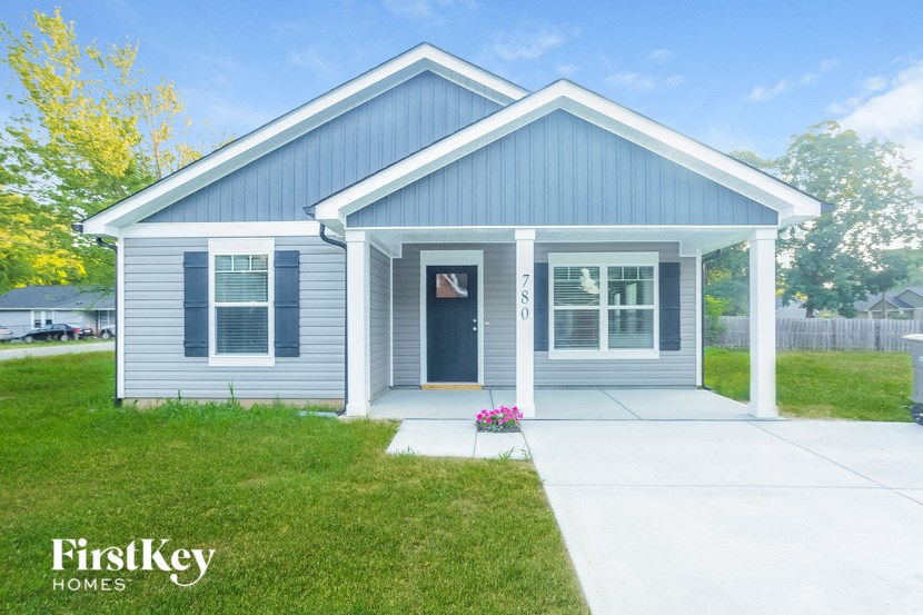 the exterior of a blue house with a sidewalk and grass