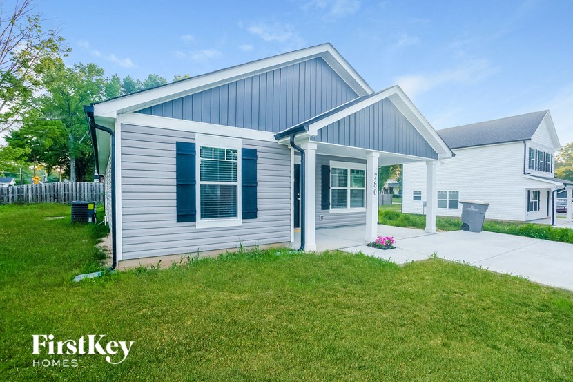 a white house with blue shutters and a lawn in front of it