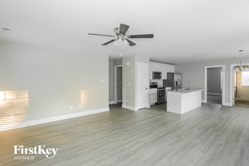 an empty living room and kitchen with a ceiling fan