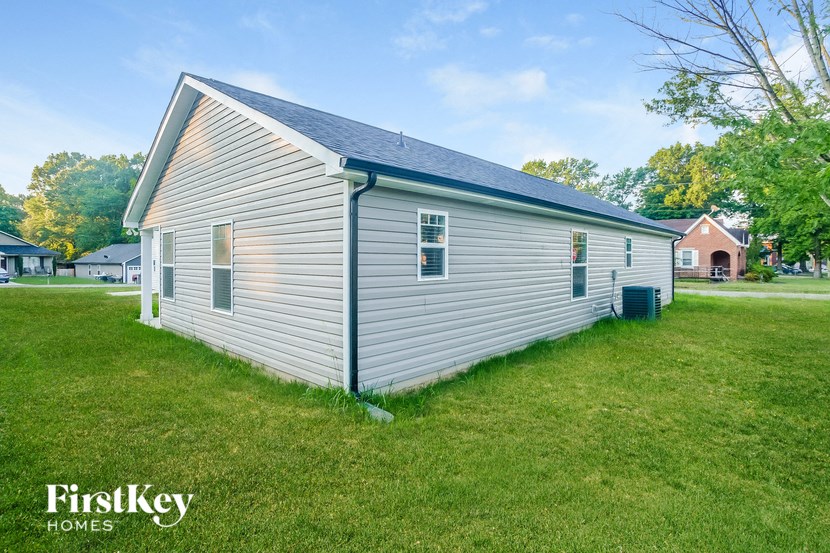 a small white house with a gray roof in a grass field