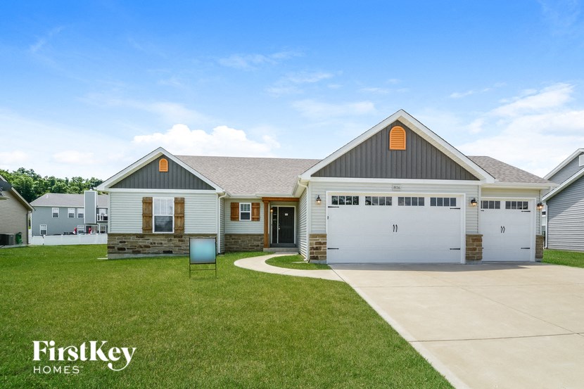 the exterior of a house with a driveway and a lawn