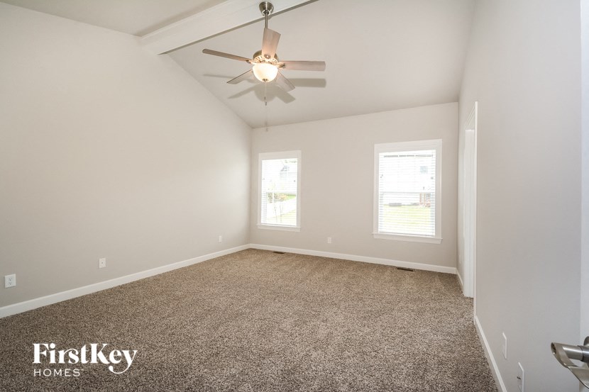 an empty living room with a ceiling fan and a window