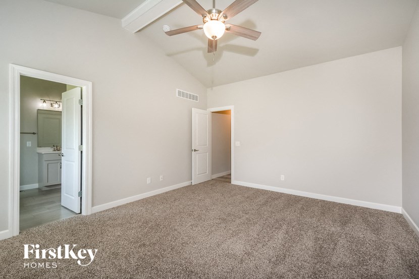 an empty living room with a ceiling fan and a door to a bathroom