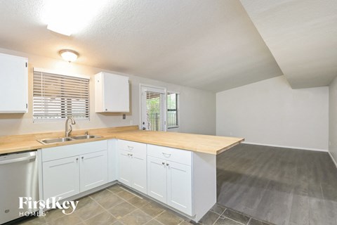 A kitchen with white cabinets and a wooden countertop.