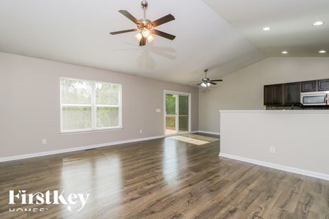 A spacious room with a ceiling fan and wooden flooring.