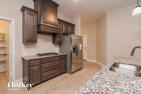 A kitchen with a granite counter top and a stainless steel refrigerator.