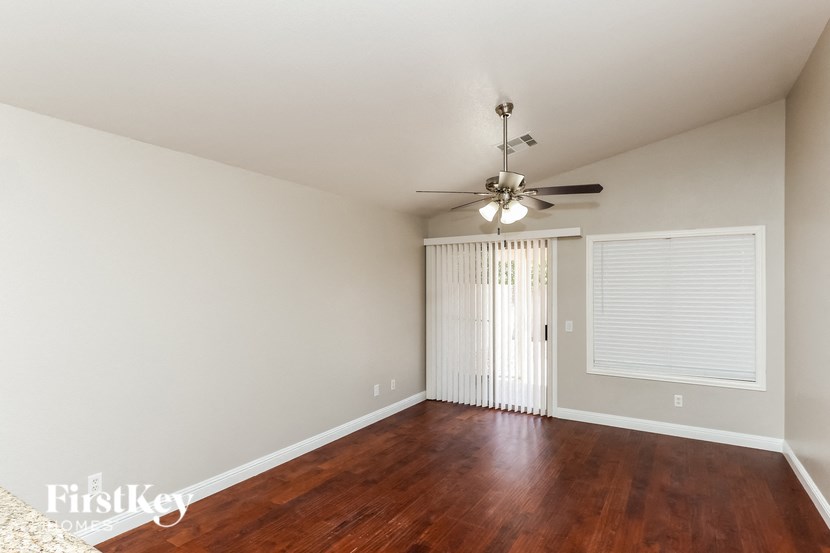an empty living room with wood flooring and a ceiling fan