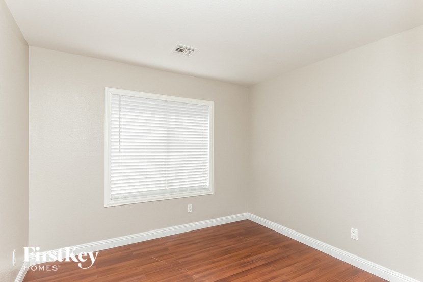 a bedroom with wood flooring and a window with a window sill