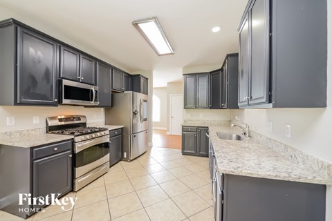 A kitchen with black cabinets and a stove top oven.