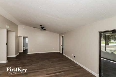 A spacious room with wooden floors and a ceiling fan.