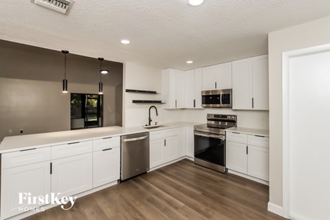 A modern kitchen with white cabinets and stainless steel appliances.