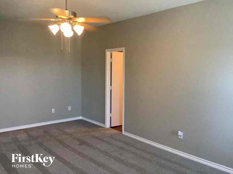 an empty living room with gray walls and a ceiling fan