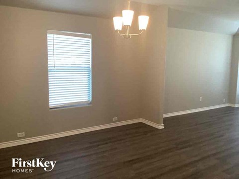 a living room with wooden floors and a window and a chandelier