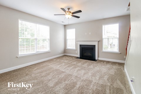 an empty living room with a fireplace and a ceiling fan