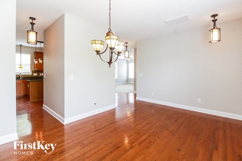 the living room and dining room with wood flooring and two chandeliers
