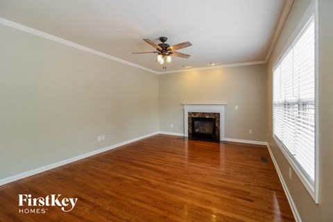 A spacious room with a fireplace and wood flooring.