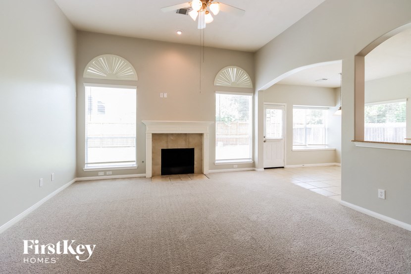 an empty living room with a fireplace and a ceiling fan