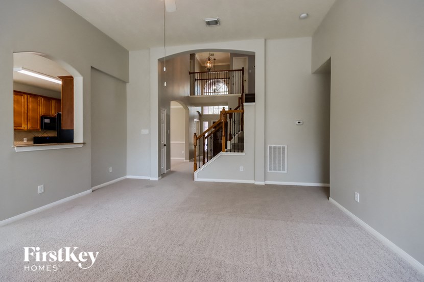 an empty living room with a staircase in the background