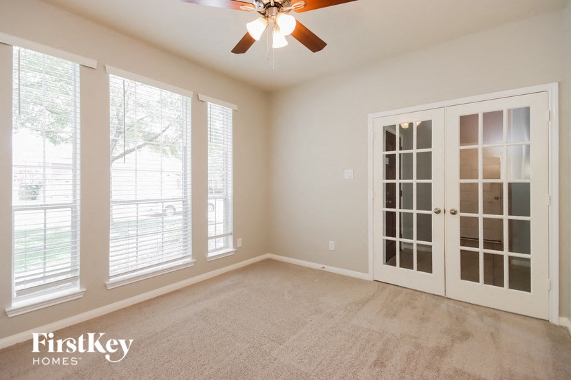an empty living room with a ceiling fan and doors