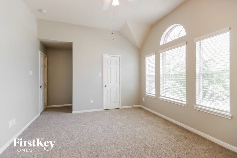 an empty living room with a white door and large windows