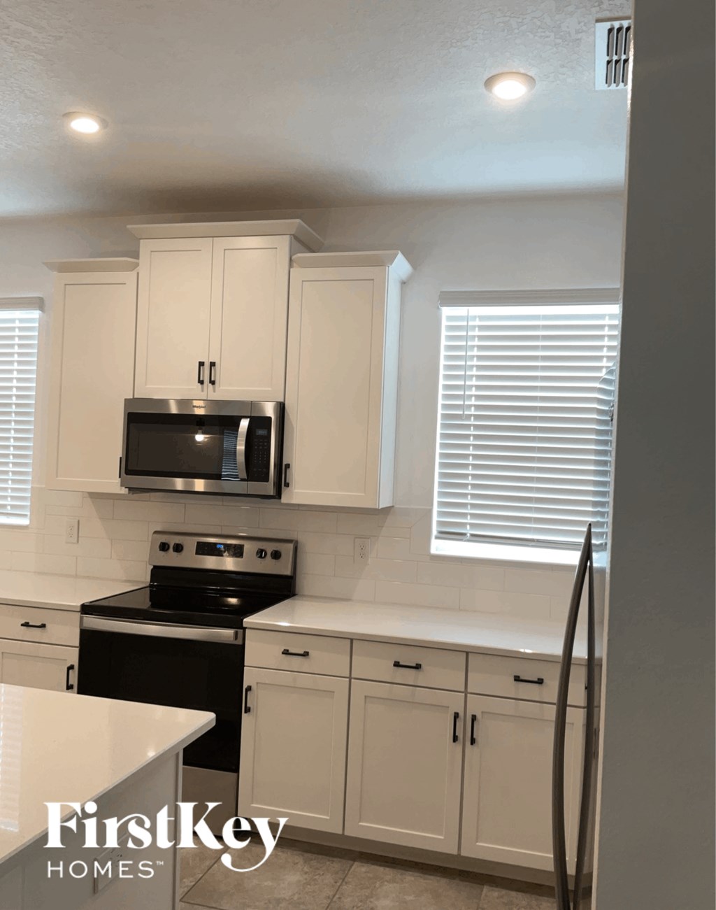 a white kitchen with white cabinets and black appliances