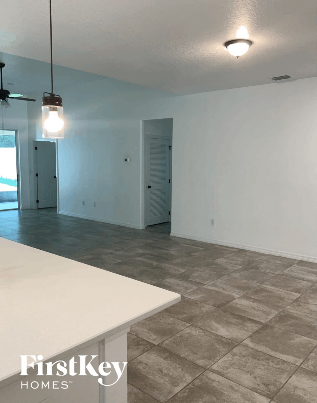 an empty kitchen and living room with white walls and tile floors