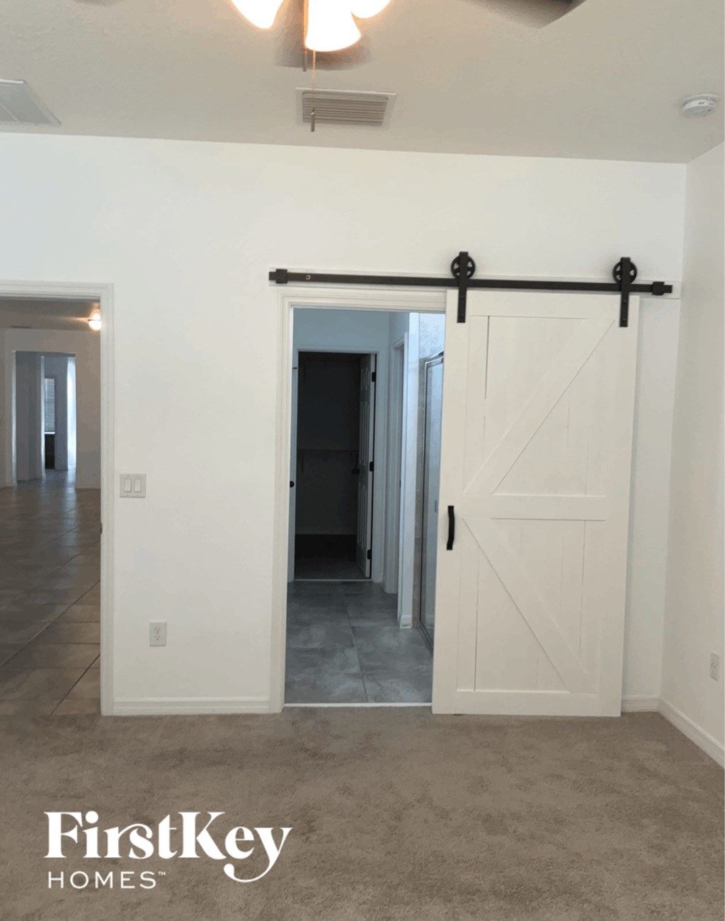 a barn door in a living room with a hallway to the closet and a hallway