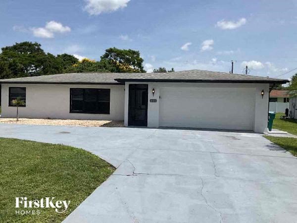 a small white house with a driveway in front of it
