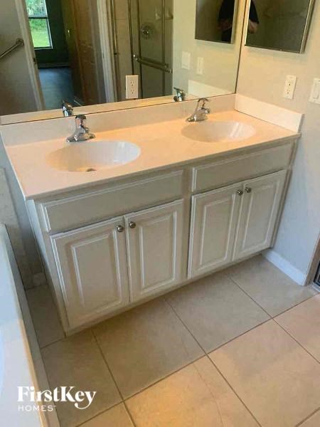A bathroom with a double sink vanity and a mirror above it.