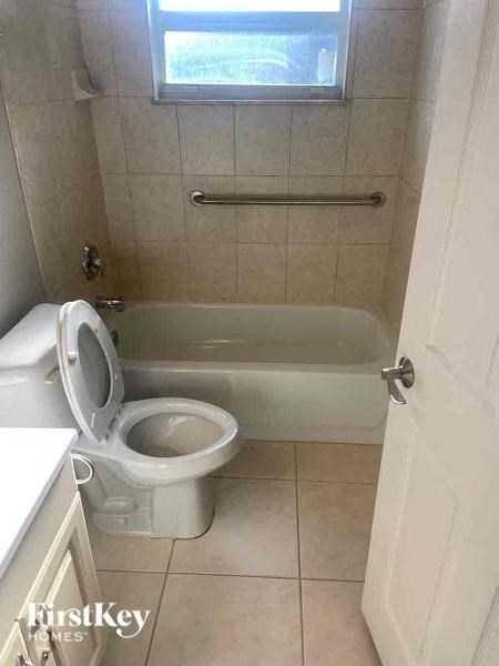 A small bathroom with a toilet, tub, and a window.