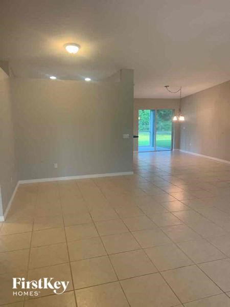 A spacious room with tiled flooring and a view of a green outdoor area through a glass door.