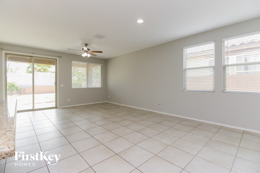 an empty living room with a ceiling fan and tiled floor