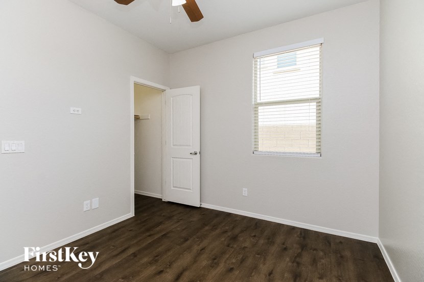 a bedroom with white walls and wood flooring and a closet