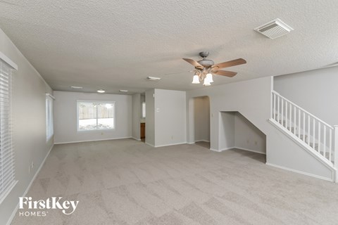 A spacious room with a fan and carpeted floor.