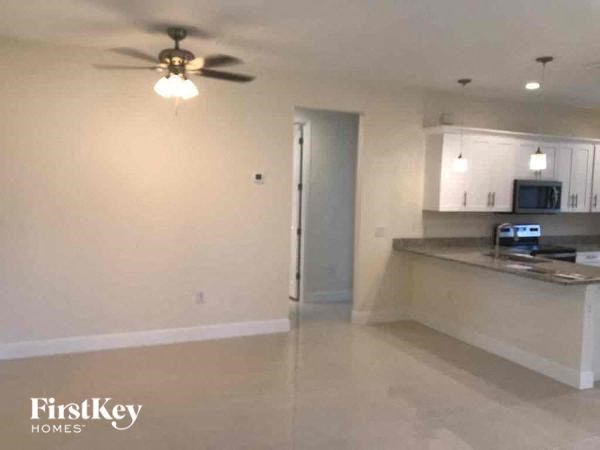 an empty living room and kitchen with a ceiling fan