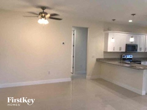 an empty living room and kitchen with a ceiling fan